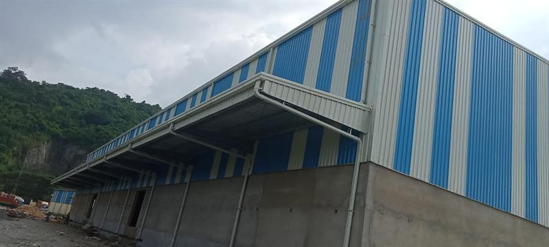 Blue and white clad shed with an entry canopy and hills behind