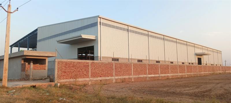 Completed pre-engineered warehouse behind a boundary wall